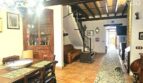 Rustikales Wohnzimmer mit Holzbalkendecke, Esstisch, Treppe und Terrakottaboden im Stadthaus Petra