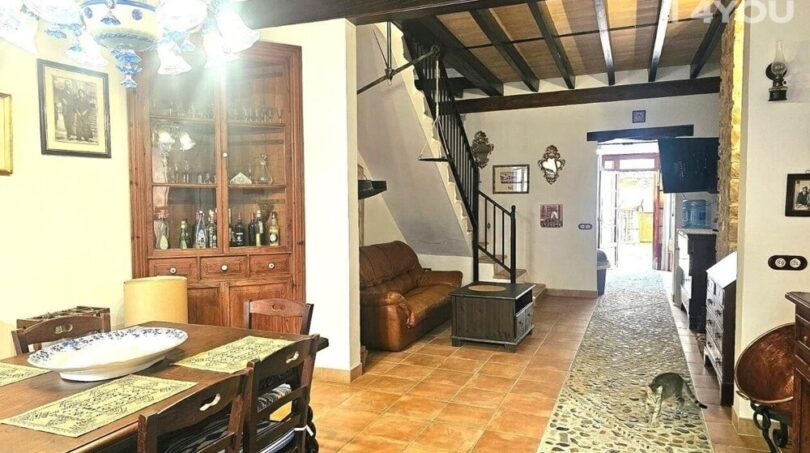 Rustikales Wohnzimmer mit Holzbalkendecke, Esstisch, Treppe und Terrakottaboden im Stadthaus Petra