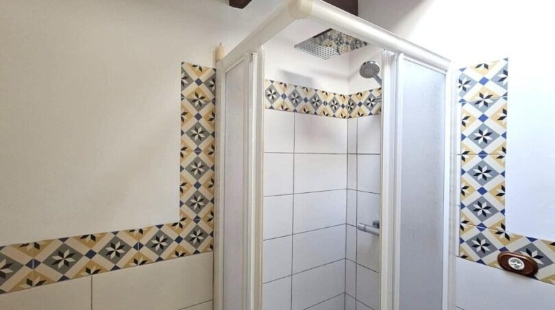 Dusche mit gemusterten Zementfliesen und weißen Wandfliesen im modernisierten Stadthaus in Petra
