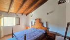 Schlafzimmer mit Holzbalkenkeller, antikem Holzbett, Nachttischen und Terrakottaboden im Stadthaus Petra