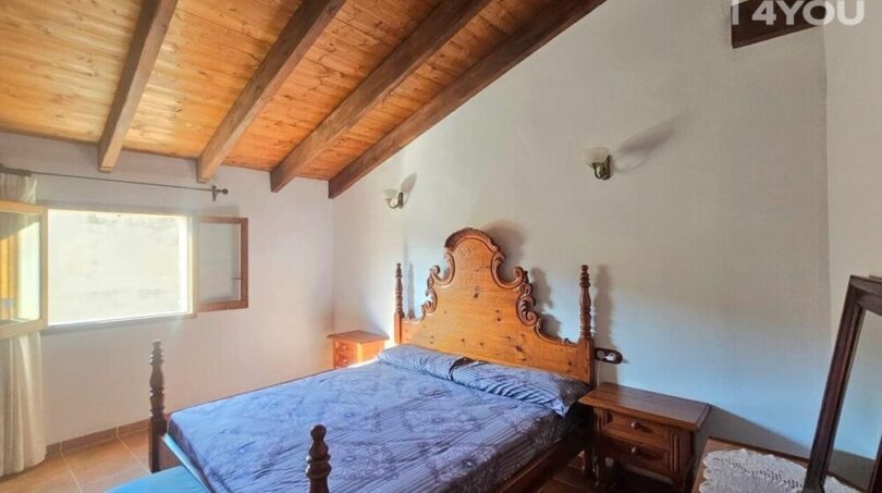 Schlafzimmer mit Holzbalkenkeller, antikem Holzbett, Nachttischen und Terrakottaboden im Stadthaus Petra