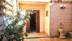 Mediterraner Innenpatio mit Holzlamellentür, Natursteinbrunnen, Bougainvillea und Terrakottafliesen eines Stadthauses in Petra