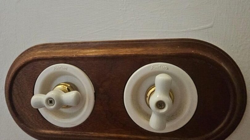 Vintage Lichtschalter aus Porzellan auf Holzplatte mit Messingdetails im modernisierten Stadthaus Petra