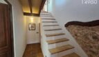 Escalera rústica con peldaños de madera, pared de piedra natural y techo de vigas de madera en casa de pueblo Petra