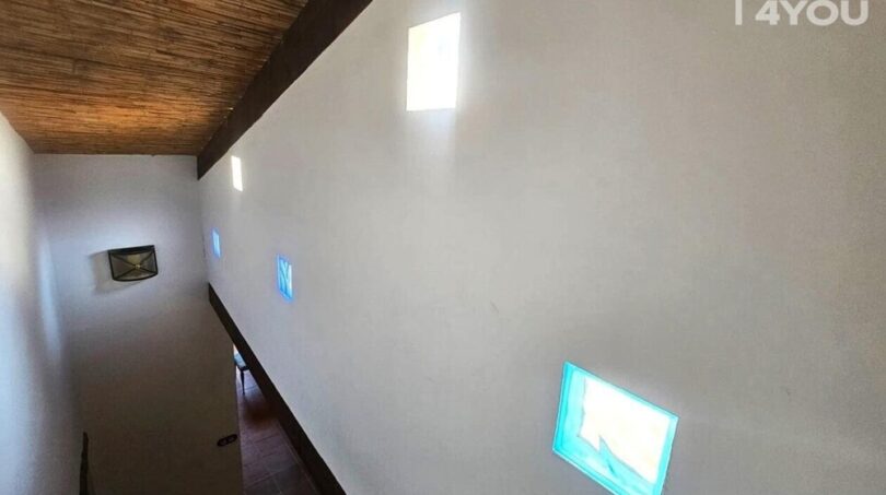 Treppenhaus mit Glasbausteinfen in Blau, Holzbalkendecke und Terrakottaboden im Stadthaus Petra