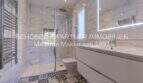 Modernes Badezimmer mit Marmorfliesen, begehbarer Dusche, WC und beleuchtetem Spiegel in mediterraner Villa Sa Coma