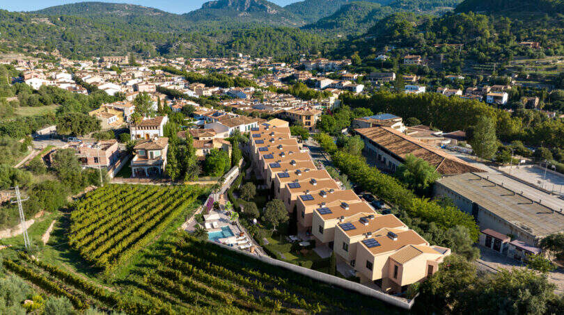 Luftaufnahme Reihenhäuser in Esporles, umgeben von Weinbergen und Tramuntana-Gebirge, Pool sichtbar.
