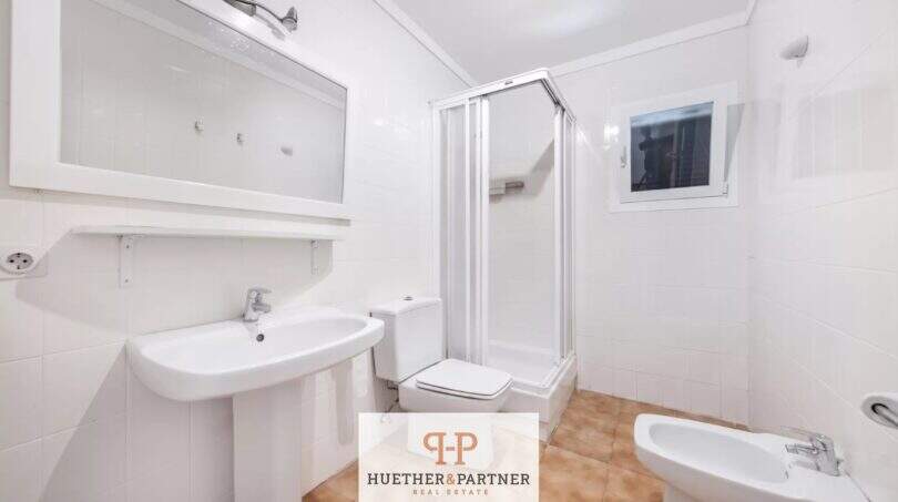 Helles Badezimmer der Erdgeschosswohnung in Cala Mandía mit Dusche, Bidet, WC und weißen Fliesen.
