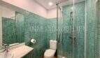 Badezimmer der Dachgeschosswohnung Blanquerna Palma mit grünen Mosaikfliesen, Glasdusche und Marmorwaschbecken