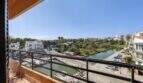 Balkon mit Metallgeländer, Blick auf den Hafen von Porto Cristo, Kanal, Boote und Grünflächen