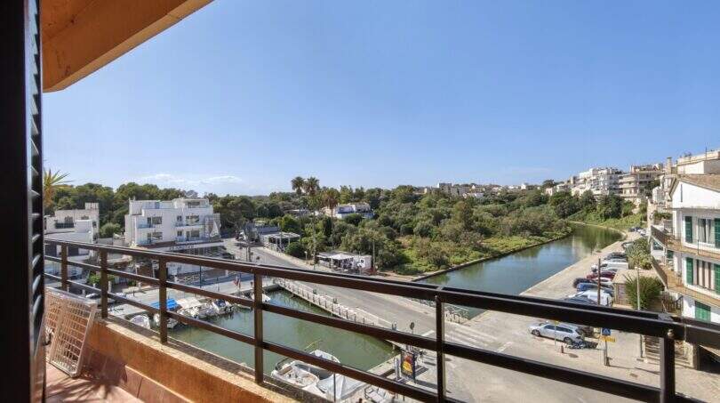 Balkon mit Metallgeländer, Blick auf den Hafen von Porto Cristo, Kanal, Boote und Grünflächen