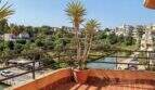 Sonnige Dachterrasse mit Yucca-Pflanze, Blick auf den Hafen von Porto Cristo und üppige Vegetation.