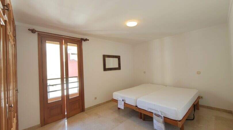 Helles Schlafzimmer mit zwei Einzelbetten, Balkon mit Holztüren und Wandspiegel in Hafenwohnung Porto Cristo