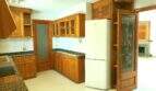 Geräumige Küche mit Holzschränken, Granit-Arbeitsplatten und Kühlschrank in der Hafenwohnung Porto Cristo