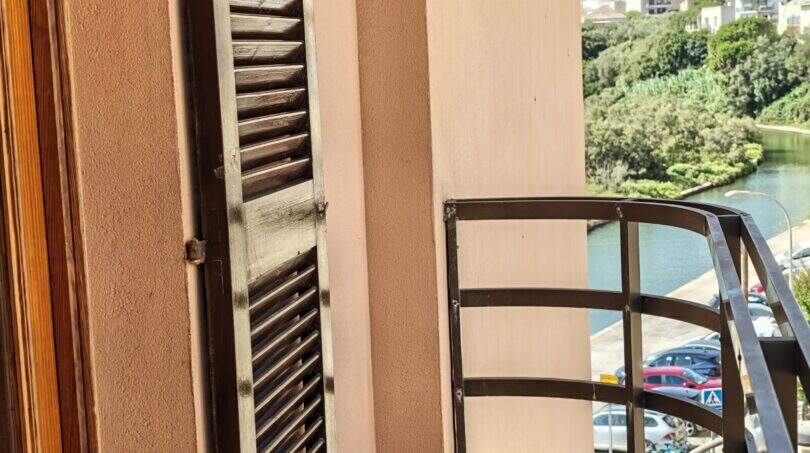 Balkon mit Metallgeländer und Lamellenläden, Blick auf Hafen und Grünanlage in Porto Cristo