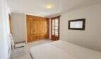 Schlafzimmer der Hafenwohnung Porto Cristo mit Doppelbett, Holzeinbauschrank und Balkonzugang