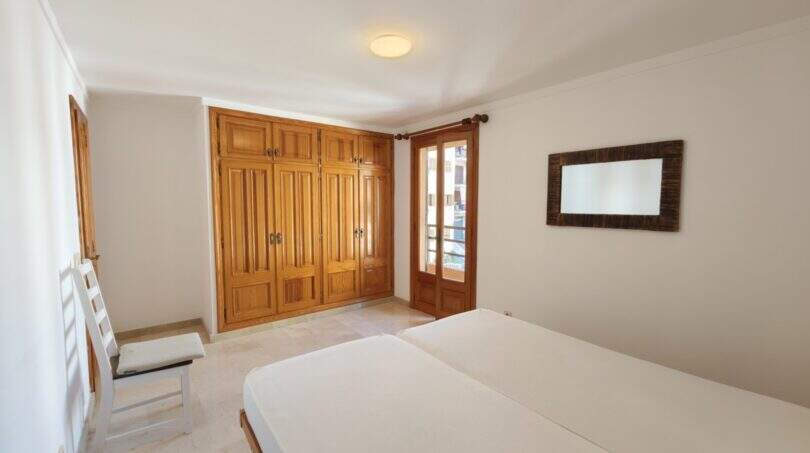 Schlafzimmer der Hafenwohnung Porto Cristo mit Doppelbett, Holzeinbauschrank und Balkonzugang