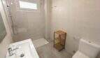 Modernes Badezimmer der Hafenwohnung Porto Cristo mit Dusche, WC, Waschbecken und Holzregal