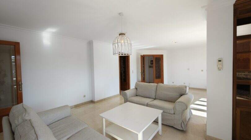 Helles Wohnzimmer mit grauem Sofa-Set, weißem Couchtisch und Pendelleuchte in Portocristó Hafenwohnung