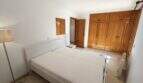 Helles Schlafzimmer mit Doppelbett, großem Holzeinbauschrank und Parkettboden in Wohnung Porto Cristo