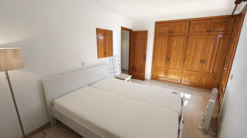 Helles Schlafzimmer mit Doppelbett, großem Holzeinbauschrank und Parkettboden in Wohnung Porto Cristo