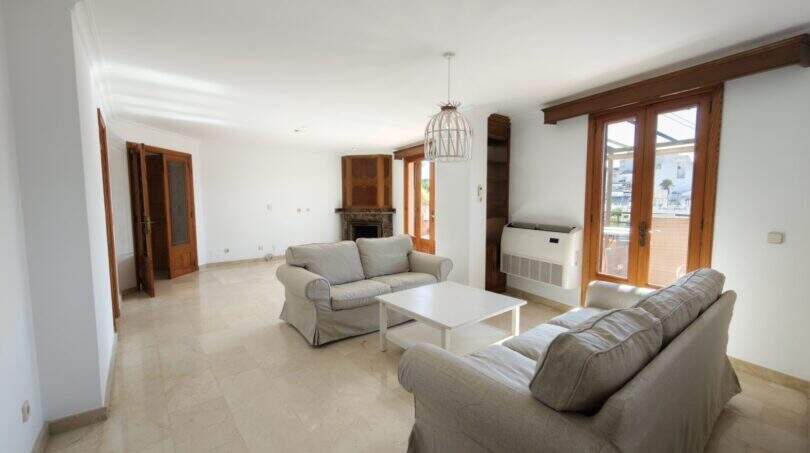 Helles Wohnzimmer mit zwei grauen Sofas, Kamin, Klimaanlage und Holztüren zur Terrasse in Porto Cristo