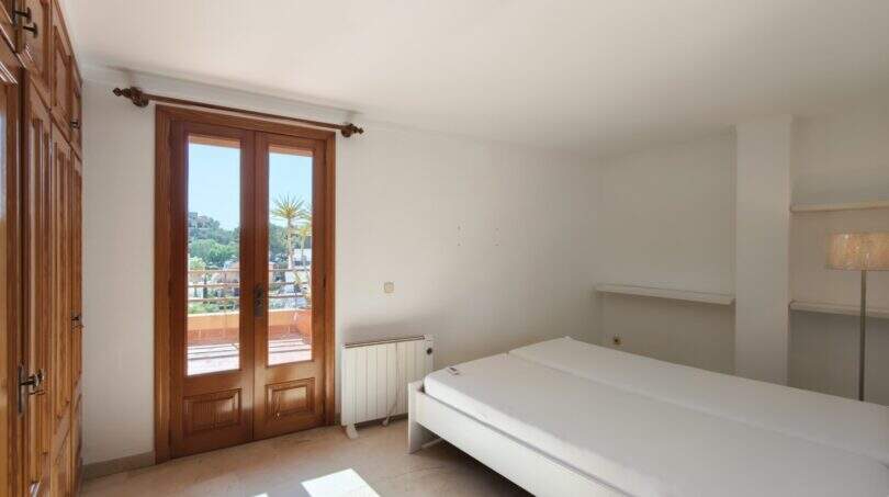 Helles Schlafzimmer mit Doppelbett, Holzschrank und Terrassentür mit Meerblick in Porto Cristo