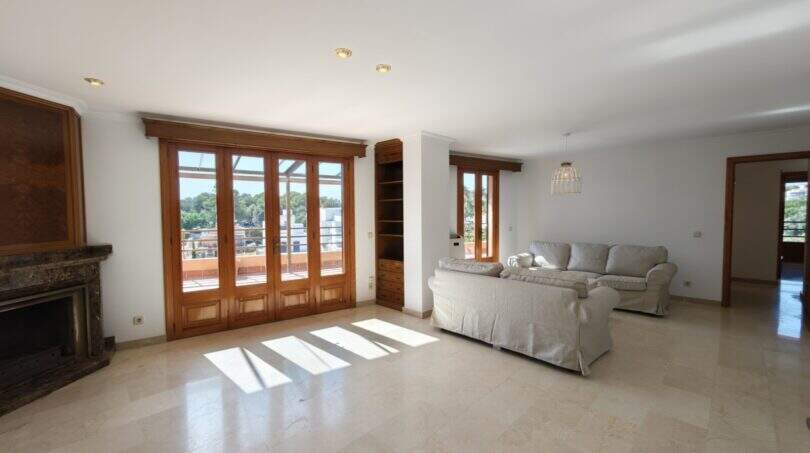 Helles Wohnzimmer mit Marmorboden, Kamin, Holztüren zur Terrasse und Meerblick in Porto Cristo