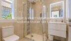 Modernes Badezimmer der mediterranen Villa in Sa Coma mit Glasdusche, WC und elegantem Waschtisch.