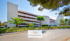 Außenansicht Apartment-Komplex in Cales de Mallorca mit Palmen, gepflegter Grünanlage und rotem Klinkerfassade.