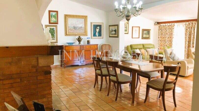Rustikales Wohnzimmer mit Terrakottaboden, Holzesstisch, Kamin und Gemälden in Haus in S'Aranjassa, Palma.