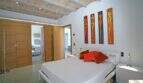 Helles Schlafzimmer der Finca Felanitx mit Doppelbett, Gewölbedecke, Holzschiebetüren und farbenfrohen Wandgemälden.