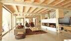 Geräumiges Wohnzimmer der Finca Felanitx mit Kamin, Natursteinwänden, gewölbter Holzdecke und modernem TV-Bereich.