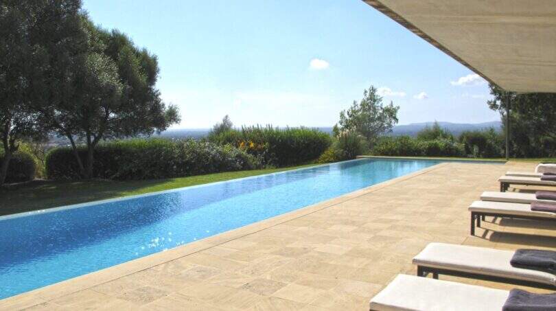 Infinity-Pool mit Natursteintetrasse, Liegestühlen und Weitblick über die Landschaft von Felanitx