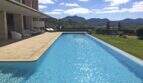 Großer Infinity-Pool mit Sandsteintetrasse, Loungebereich und Bergpanorama der modernen Finca in Felanitx