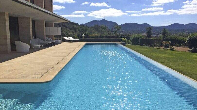 Großer Infinity-Pool mit Sandsteintetrasse, Loungebereich und Bergpanorama der modernen Finca in Felanitx