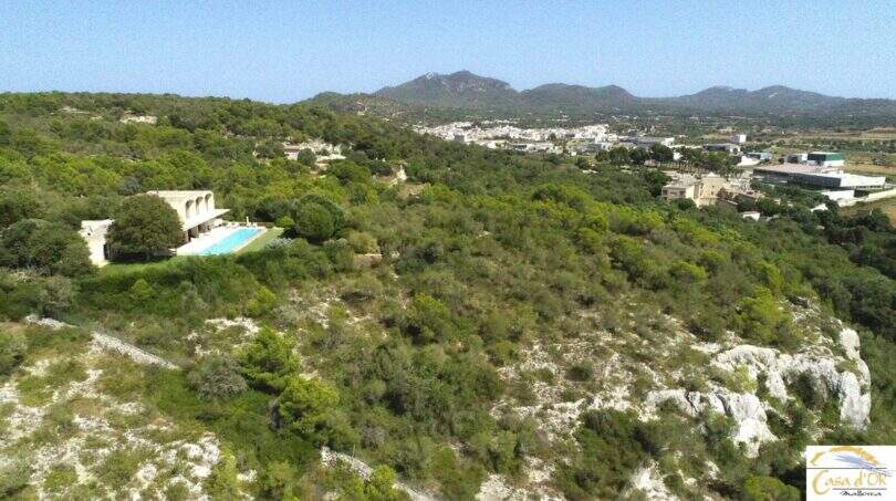 Luftaufnahme moderne Finca Felanitx mit Infinity-Pool, umgeben von grüner Landschaft und Blick auf Berge