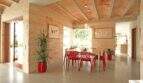 Esszimmer der Finca Felanitx mit roten Designerstühlen, Natursteinwänden und traditioneller Holzbalkendecke