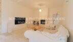 Helles Wohnzimmer mit weißem Sofa, Holztisch, TV und Gewölbedecke im sanierten Landhaus in Port de Manacor