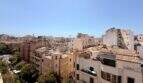 Panoramablick über die Altstadt von Palma de Mallorca mit historischen Gebäuden und Terrakotta-Dächern bei blauem Himmel.
