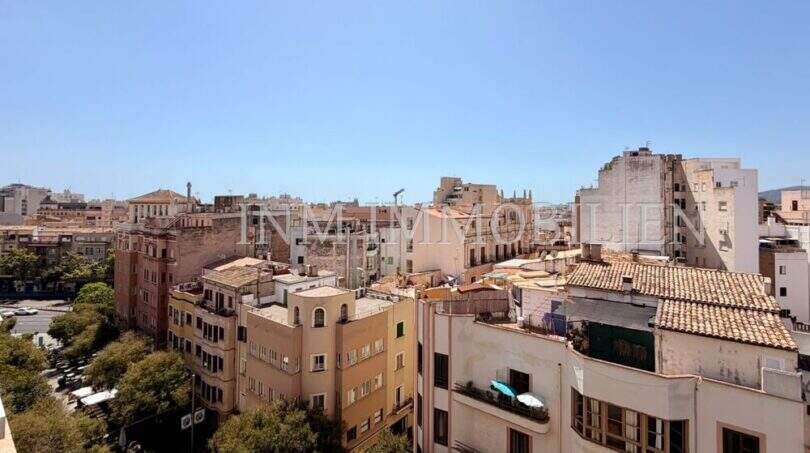 Panoramablick über die Altstadt von Palma de Mallorca mit historischen Gebäuden und Terrakotta-Dächern bei blauem Himmel.