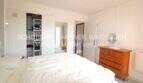 Dormitorio luminoso con cama doble, cómoda de madera y armario empotrado abierto en apartamento en Cala Ratjada