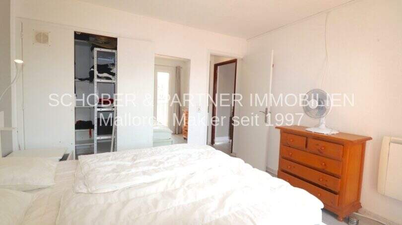 Helles Schlafzimmer mit Doppelbett, Holzkommode und offenem Einbauschrank in Wohnung in Cala Ratjada