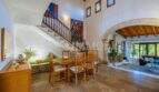 Helles Esszimmer mit Holztreppe, Steinbogen und Natursteinboden im mediterranen Einfamilienhaus Sa Coma.