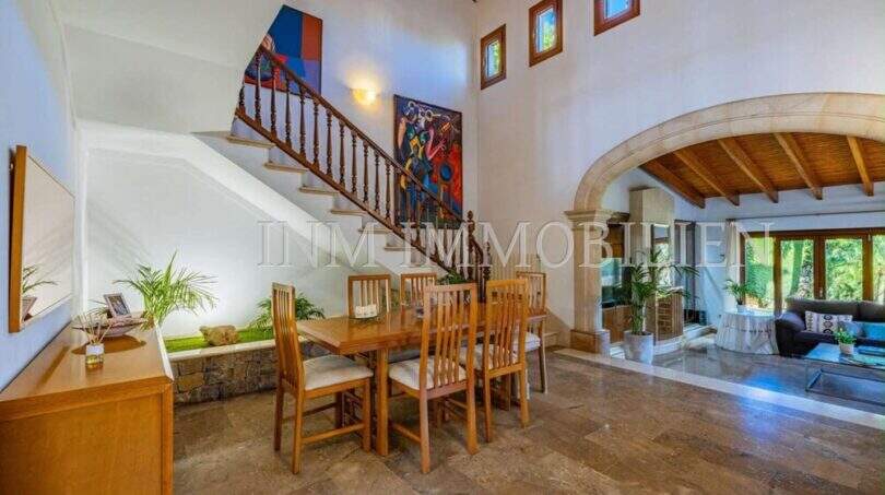 Helles Esszimmer mit Holztreppe, Steinbogen und Natursteinboden im mediterranen Einfamilienhaus Sa Coma.
