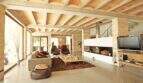 Helles Wohnzimmer der Designer-Finca in Felanitx mit Gewölbedecke, Kamin, modernen Sesseln und großen Fensterfronten.