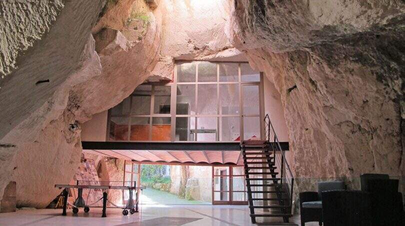Spektakulärer Wohnbereich in natürlicher Höhle mit Glasfront, Mezzanin-Ebene und Stahltreppe der Designer-Finca Felanitx