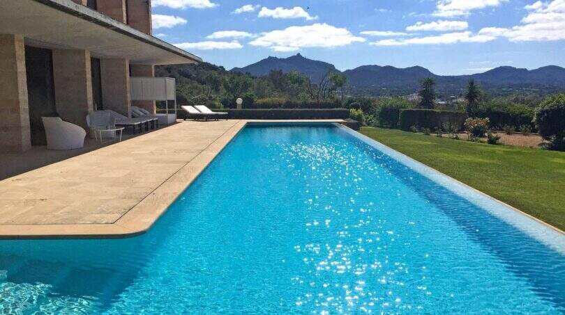 Infinity-Pool der Designer-Finca in Felanitx mit Bergpanorama, Sonnenliegen und moderner Architektur