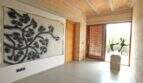 Eingangsbereich der Designer-Finca mit großem Kunstgemälde, Holzdecke und Skulptur neben Glastür.