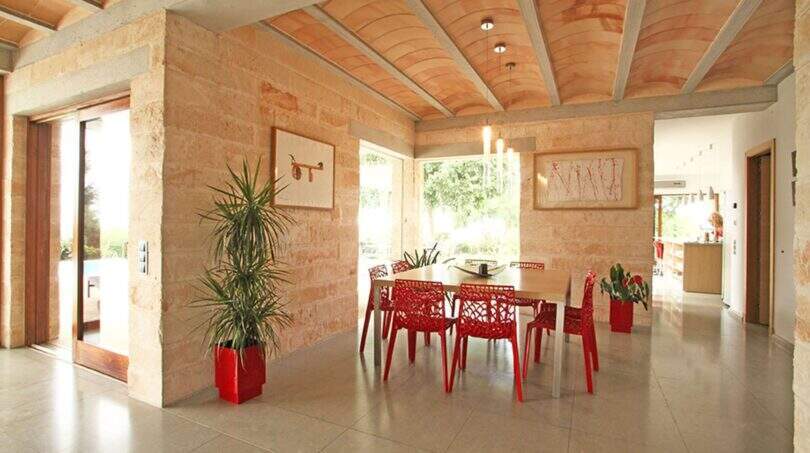 Helles Esszimmer der Designer-Finca mit roten Stühlen, Natursteinwänden und elegantem Gewölbedecke in Felanitx.